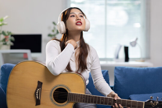 Young woman enjoying music and playing guitar.