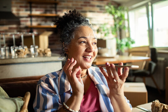 Smiling senior woman speaking into smartphone at home