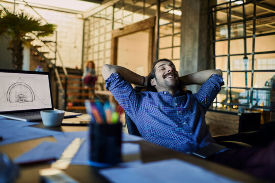 Smiling man leaning back at desk in creative office
