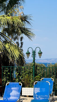 Blue sun loungers and green wooden parasol by turquoise swimming pool with sea view, Corfu, Greece