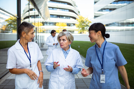 Medical team walking and talking outside modern hospital