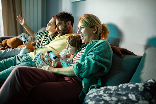 Family playing video games together on sofa