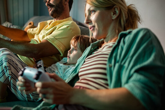 Couple playing video game on sofa with child