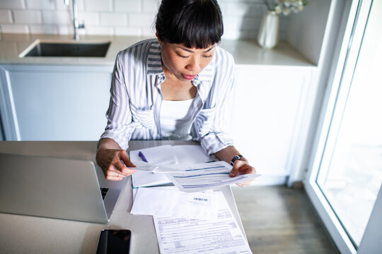 Woman reviewing household bills at kitchen counter