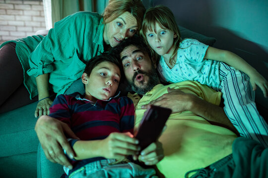 Family reacting to smartphone video on the couch