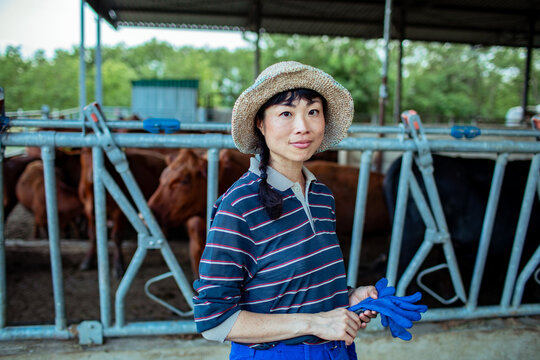 Woman farmer holding work gloves in cattle barn