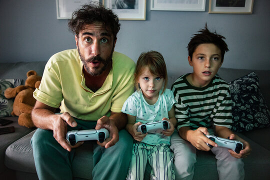 Man and two kids playing video game at home