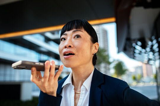 Businesswoman using voice command on smartphone outdoors