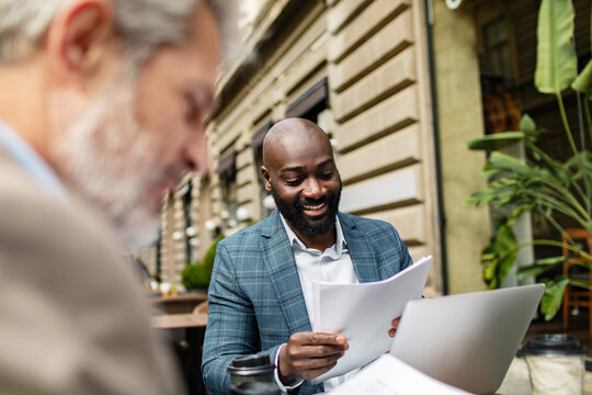 Smiling businessman reviewing paperwork at outdoor cafe