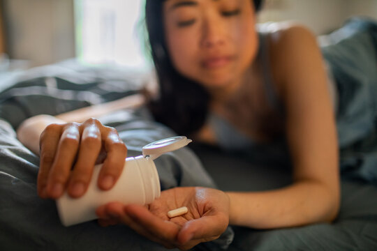 Woman taking a pill in bed at home