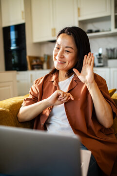 Smiling woman waving during video call at home