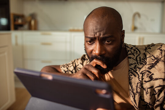 Concerned man looking at tablet in home kitchen