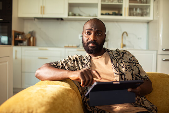 Man tapping tablet on sofa in home kitchen