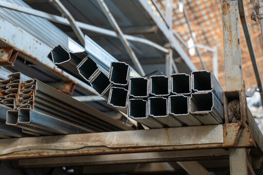 Square steel pipes stacked on metal storage racks in warehouse