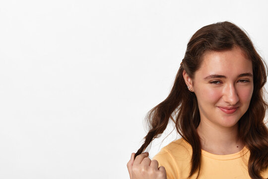 Teen counseling, skeptical teenage girl with ironic doubtful expression twirls a strand of her hair, isolated on white background, concept of distrust and adolescent emotions