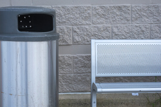 Metal bench and trash can against concrete block wall
