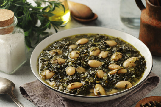 A bowl with traditional Tuscan kale salad and white beans soup Cavolo nero e fagioli