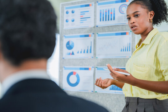 Confident businessman in suit explaining ideas to client across office desk during business consultation