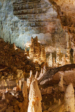 Stalactites and stalagmites in a cave Grotta di Monte Cucco in Umbria, Italy. Brown stones and crystalline deposits jut upwards.