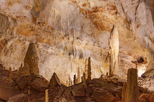 Stalactites and stalagmites in a cave Grotta di Monte Cucco in Umbria, Italy. Brown stones and crystalline deposits jut upwards.