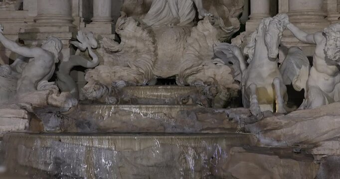 Detail view of the sculpted tritons and sea horses at Trevi Fountain at night in Rome.