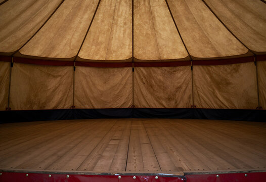 Event planning and venue rental, empty circus tent interior with wooden stage floor and canvas canopy for performance or festival gathering space