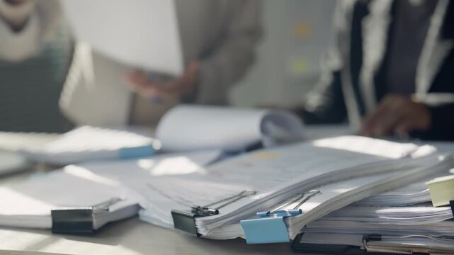 Business Professionals Reviewing Documents with Heavy Paperwork at Office Desk