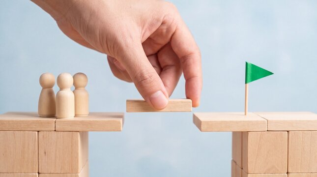 Hand placing missing block in bridge for wooden figures, closing the skills gap