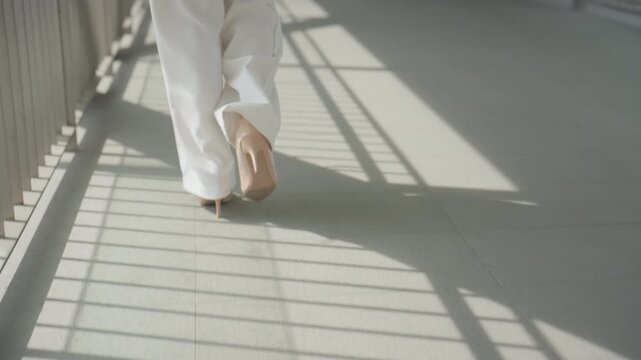 Businesswoman Walking Barefoot Through Sunlit Modern Office Corridor