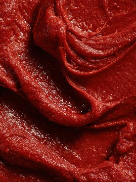 Macro close up of thick red tomato paste texture with smooth swirls and natural organic surface