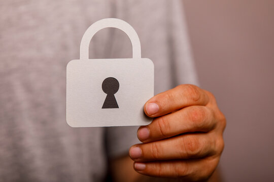 A person holds a paper cutout of a padlock, symbolizing online security and privacy.