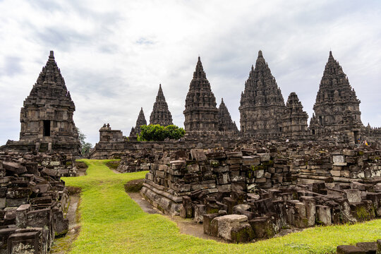 Prambanan Temple in Central Java, Indonesia. A vast 9th-century Hindu temple complex with intricate stone spires, sculptures, and ancient ruins under a cloudy sky.