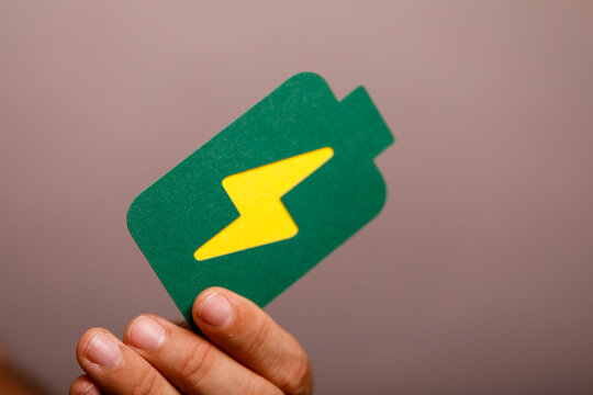 Green battery symbol held by hand, representing power, energy, and charging.