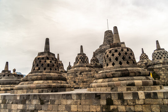 Ancient stone stupas of Borobudur, a UNESCO World Heritage Buddhist monument in Central Java, Indonesia, under an overcast sky.