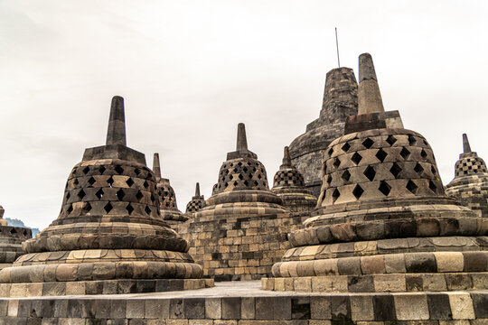 Ancient stone stupas of Borobudur, a UNESCO World Heritage Buddhist monument in Central Java, Indonesia, under an overcast sky.