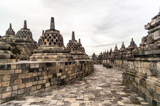 Ancient stone stupas of Borobudur, a UNESCO World Heritage Buddhist monument in Central Java, Indonesia, under an overcast sky.