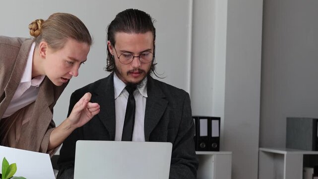 Businesswoman and businessman discussing work and analyzing data on a laptop and documents in the modern office