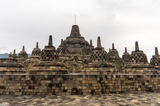 Ancient stone stupas of Borobudur, a UNESCO World Heritage Buddhist monument in Central Java, Indonesia, under an overcast sky.