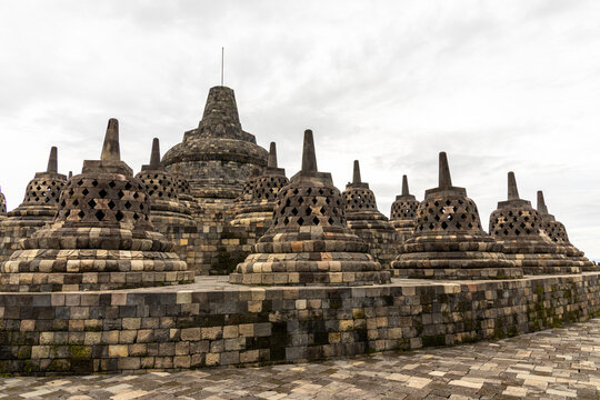 Ancient stone stupas of Borobudur, a UNESCO World Heritage Buddhist monument in Central Java, Indonesia, under an overcast sky.