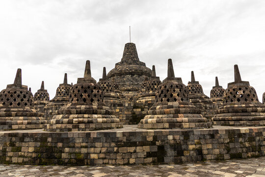 Ancient stone stupas of Borobudur, a UNESCO World Heritage Buddhist monument in Central Java, Indonesia, under an overcast sky.
