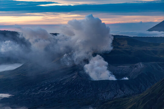 Mount Bromo volcano at sunrise, viewed from King Kong viewpoint in Bromo Tengger Semeru National Park, East Java, Indonesia. Active crater smoke, Mount Semeru cone, clouds, and vast ash plain.
