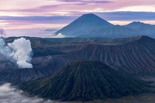 Mount Bromo volcano at sunrise, viewed from King Kong viewpoint in Bromo Tengger Semeru National Park, East Java, Indonesia. Active crater smoke, Mount Semeru cone, clouds, and vast ash plain.