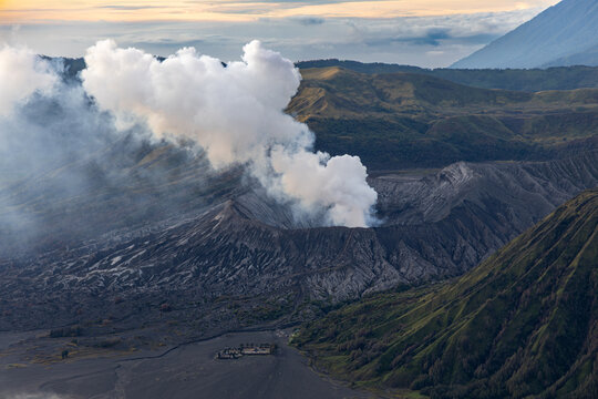 Mount Bromo volcano at sunrise, viewed from King Kong viewpoint in Bromo Tengger Semeru National Park, East Java, Indonesia. Active crater smoke, Mount Semeru cone, clouds, and vast ash plain.