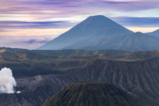 Mount Bromo volcano at sunrise, viewed from King Kong viewpoint in Bromo Tengger Semeru National Park, East Java, Indonesia. Active crater smoke, Mount Semeru cone, clouds, and vast ash plain.