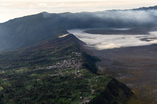 Mount Bromo volcano at sunrise, viewed from King Kong viewpoint in Bromo Tengger Semeru National Park, East Java, Indonesia. Active crater smoke, Mount Semeru cone, clouds, and vast ash plain.
