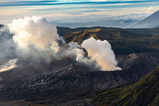 Mount Bromo volcano at sunrise, viewed from King Kong viewpoint in Bromo Tengger Semeru National Park, East Java, Indonesia. Active crater smoke, Mount Semeru cone, clouds, and vast ash plain.