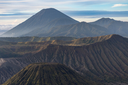 Mount Bromo volcano at sunrise, viewed from King Kong viewpoint in Bromo Tengger Semeru National Park, East Java, Indonesia. Active crater smoke, Mount Semeru cone, clouds, and vast ash plain.