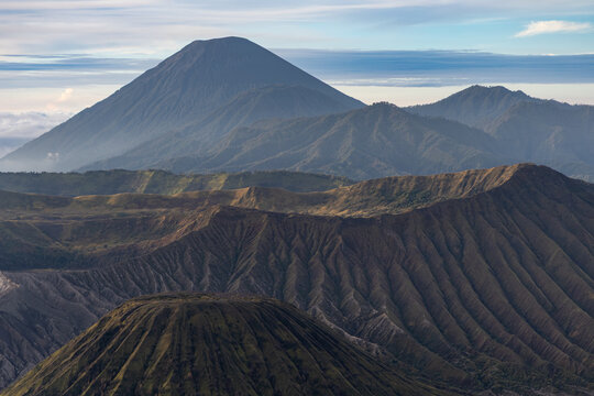 Mount Bromo volcano at sunrise, viewed from King Kong viewpoint in Bromo Tengger Semeru National Park, East Java, Indonesia. Active crater smoke, Mount Semeru cone, clouds, and vast ash plain.