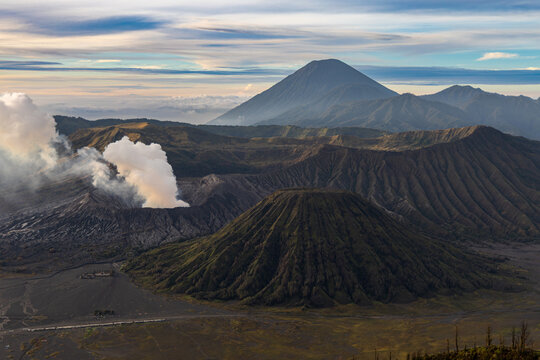 Mount Bromo volcano at sunrise, viewed from King Kong viewpoint in Bromo Tengger Semeru National Park, East Java, Indonesia. Active crater smoke, Mount Semeru cone, clouds, and vast ash plain.
