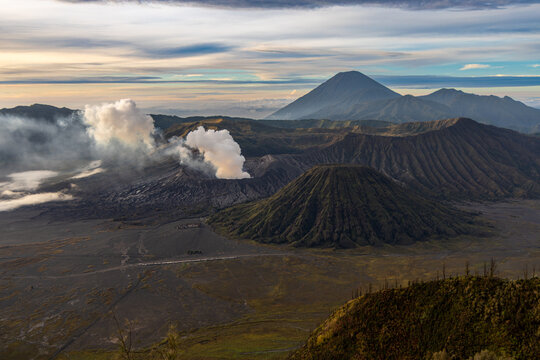 Mount Bromo volcano at sunrise, viewed from King Kong viewpoint in Bromo Tengger Semeru National Park, East Java, Indonesia. Active crater smoke, Mount Semeru cone, clouds, and vast ash plain.